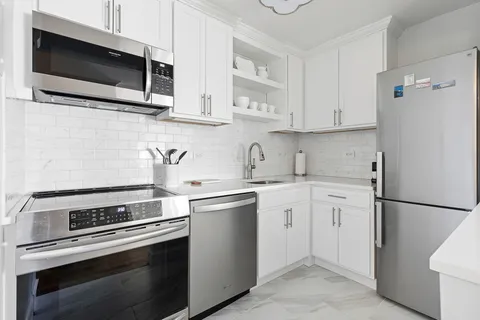 a kitchen with stainless steel appliances white cabinets granite counter tops and a view of living room