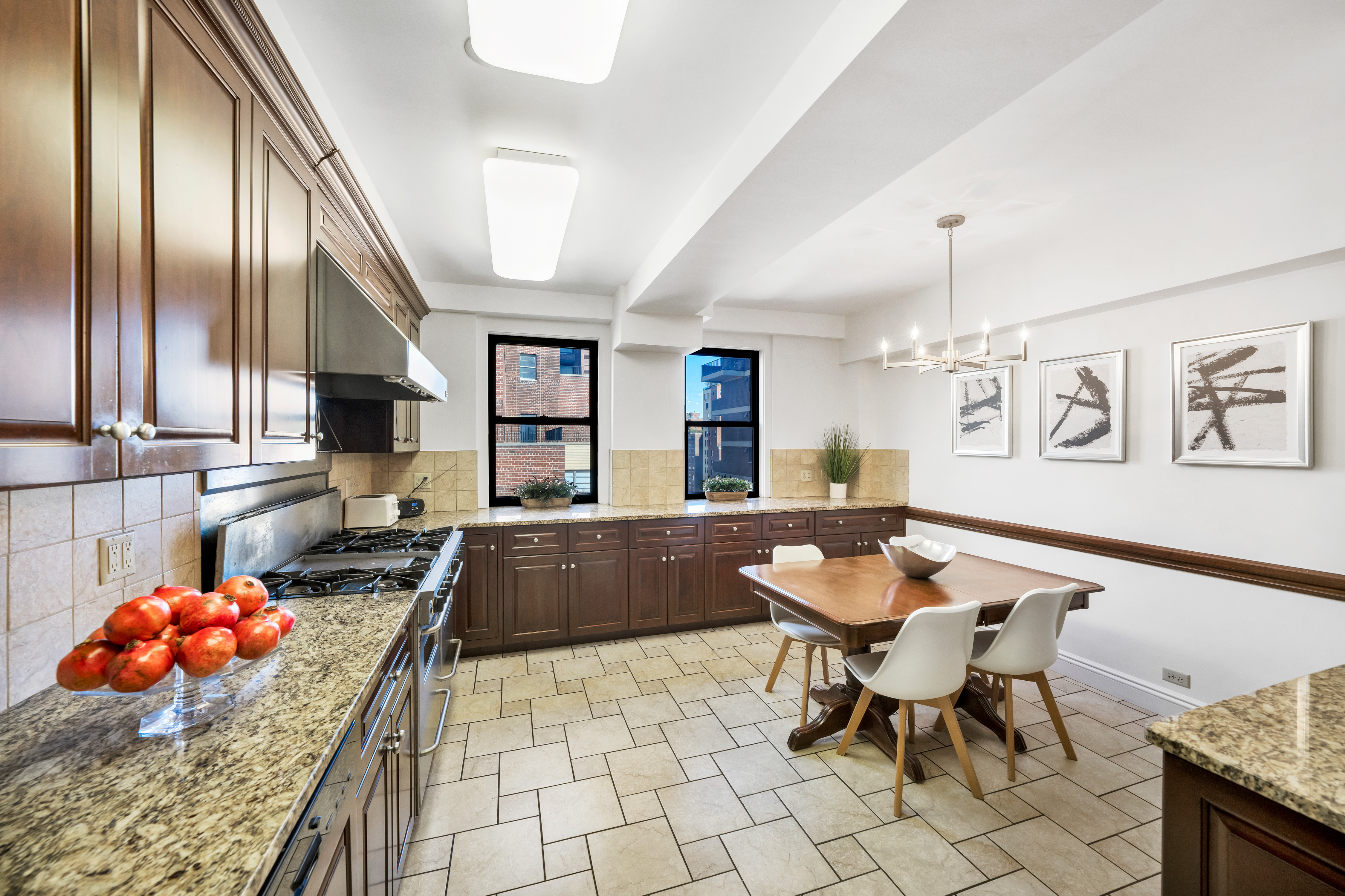 47 East 88th Street, Unit 15A Manhattan, NY 10128 - Photo 9 of 21 a kitchen with stainless steel appliances kitchen island granite countertop a table and chairs in it