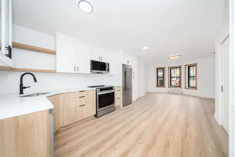 a view of a kitchen with a sink and dishwasher with wooden floor