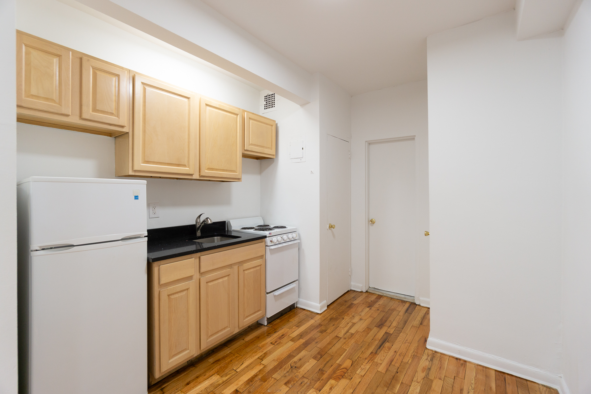 227 East 5th Street, Unit BE Manhattan, NY 10003 - Photo 3 of 7 a kitchen with granite countertop a refrigerator a stove a sink and cabinets