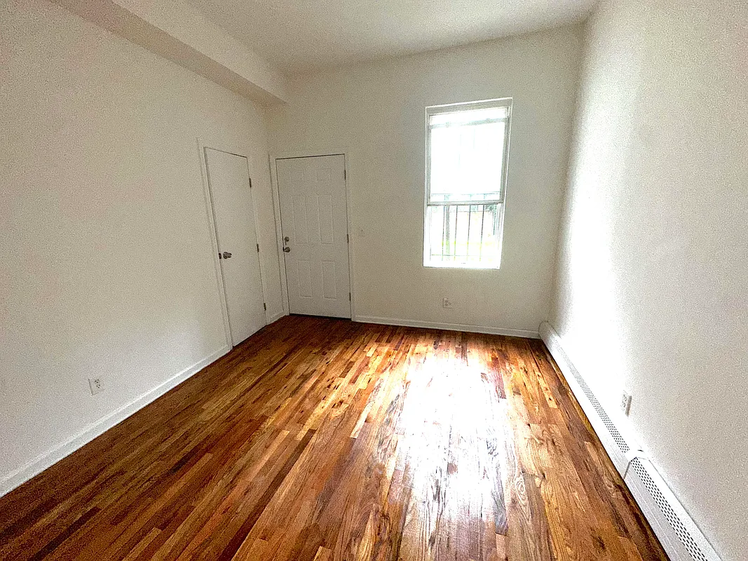 918 Dekalb Avenue, Unit 1 Brooklyn, NY 11221 - Photo 6 of 11 an empty room with wooden floor and windows