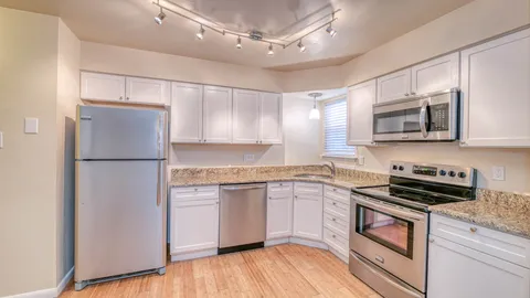 a kitchen with stainless steel appliances granite countertop a refrigerator a stove top oven a sink and dishwasher