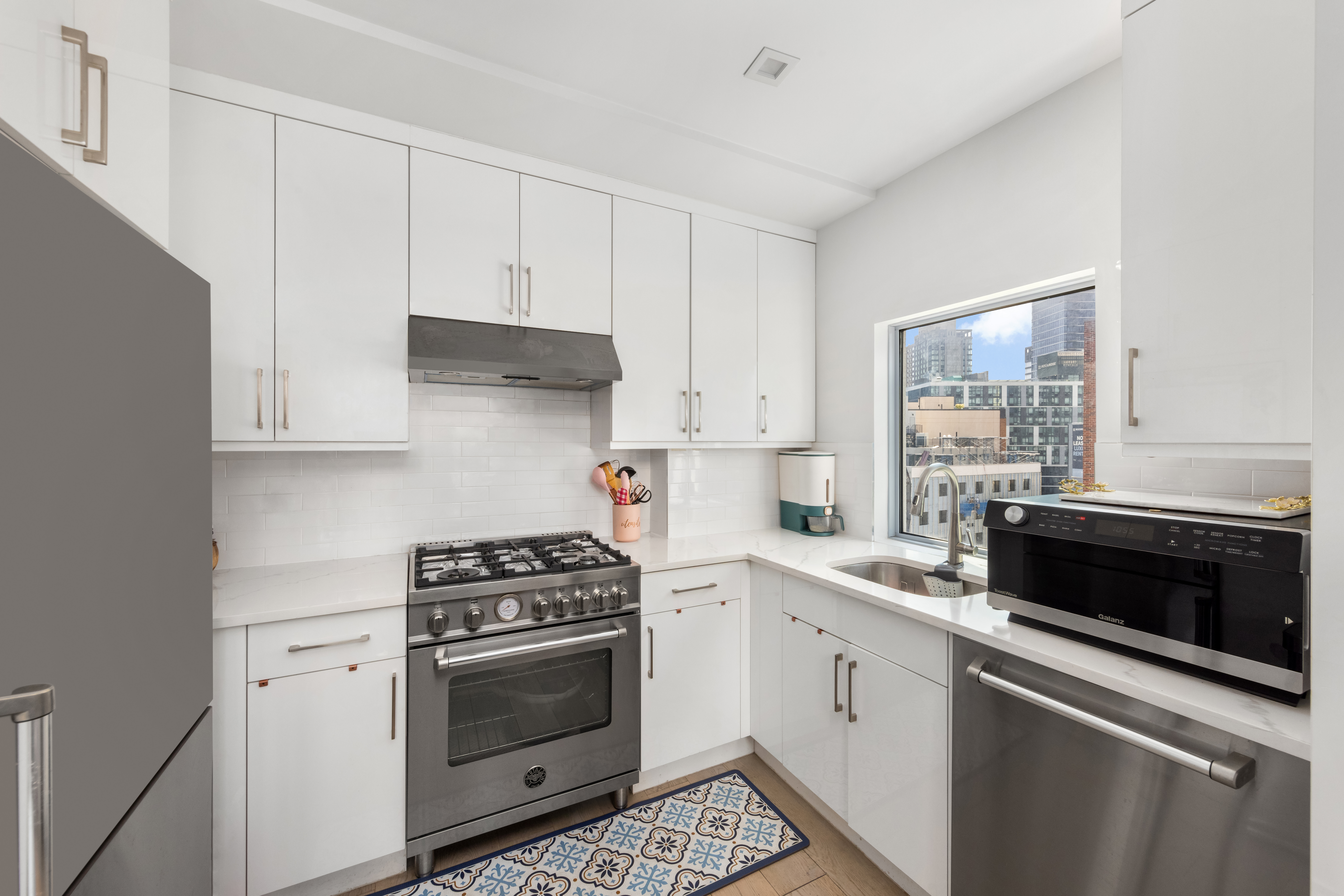 42-44 Crescent Street, Unit PHB Queens, NY 11101 - Photo 4 of 11 a kitchen with cabinets stainless steel appliances and sink