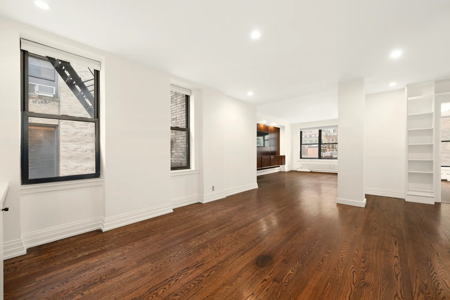 a view of a big room with wooden floor and windows