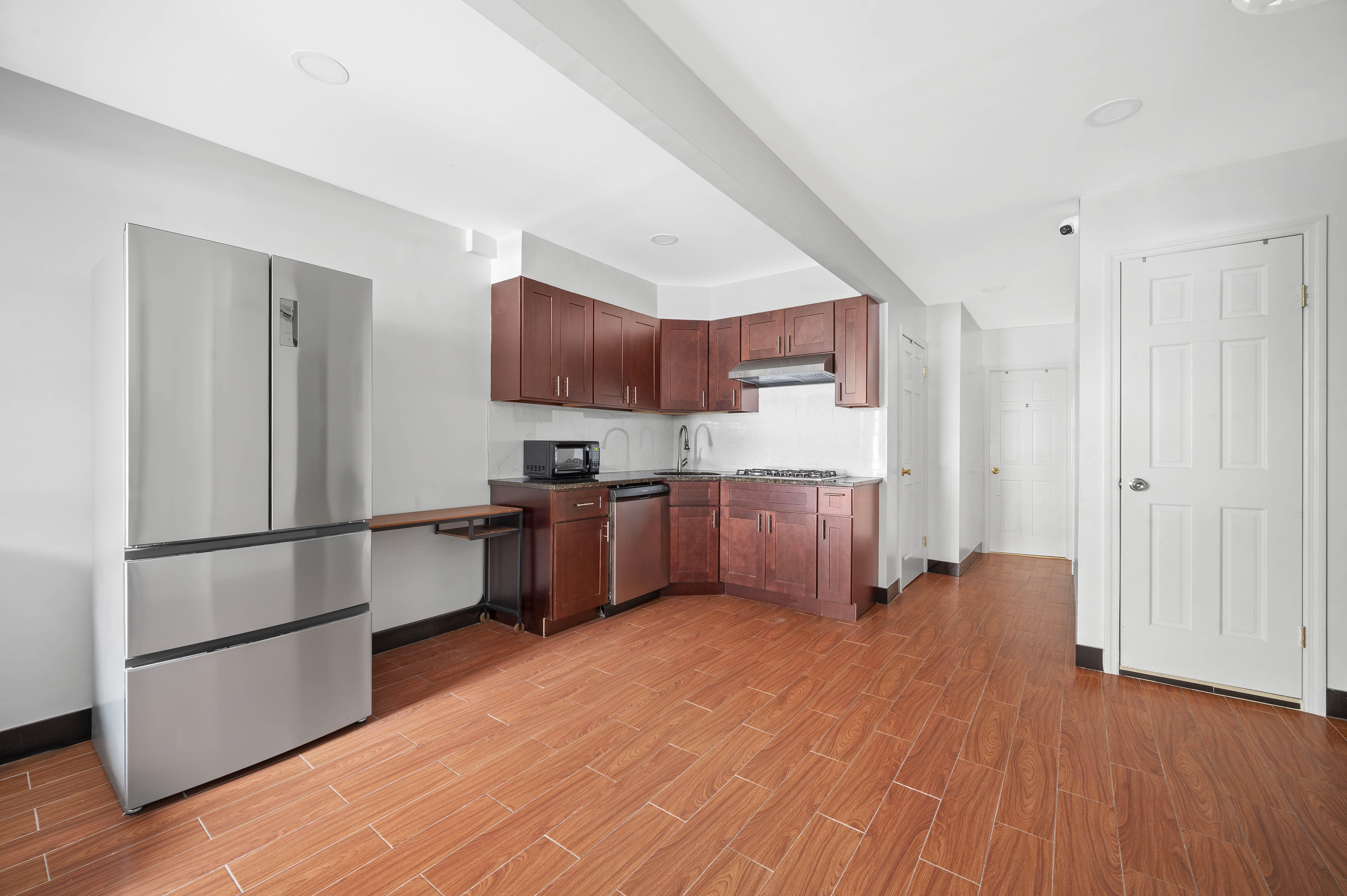 40 East Broadway, Unit 5 Manhattan, NY 10002 - Photo 2 of 10 a kitchen with stainless steel appliances a refrigerator and a wooden floor