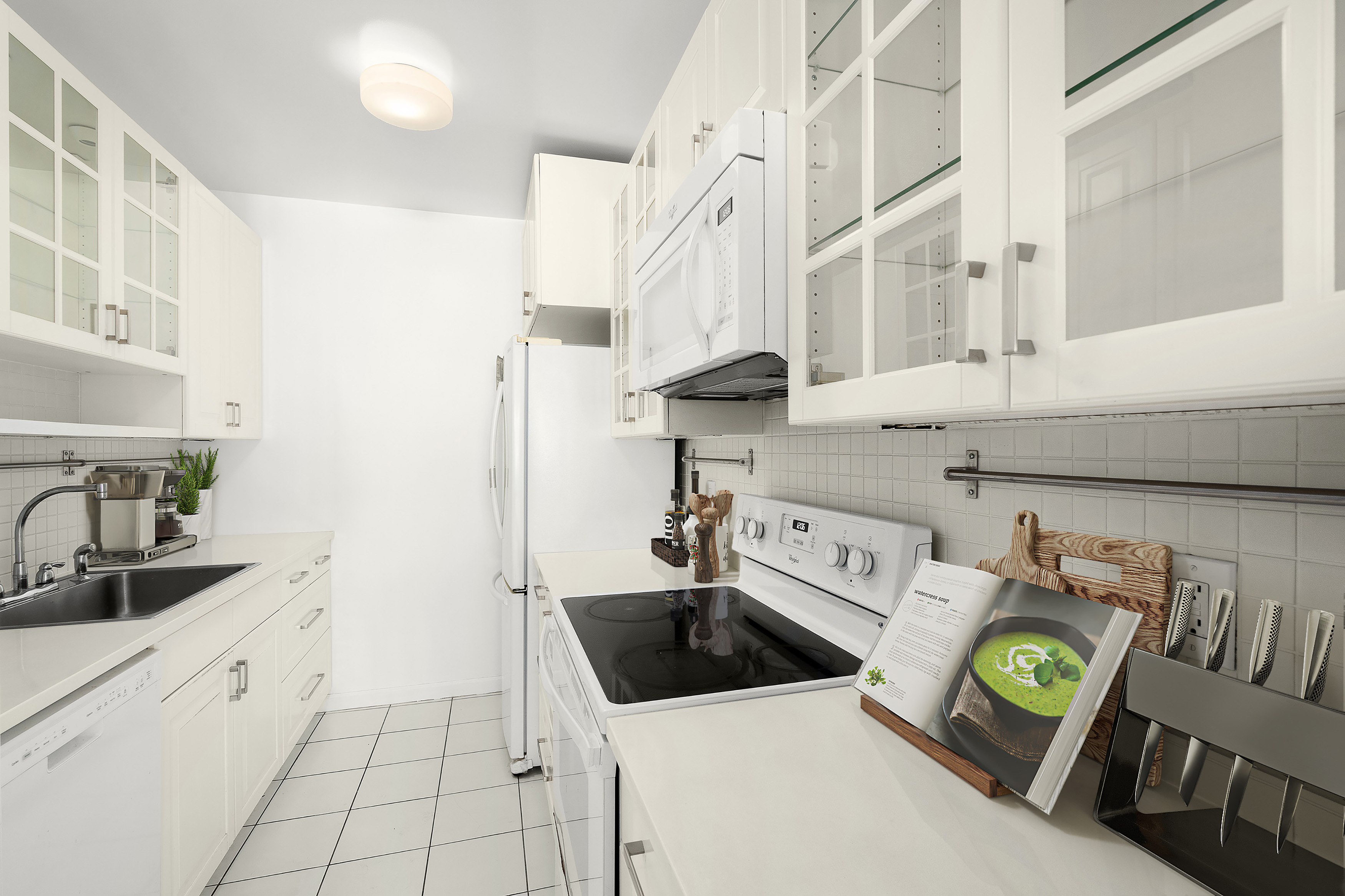 240 East 47th Street, Unit 4B Manhattan, NY 10017 - Photo 5 of 25 a kitchen with a stove a sink and a refrigerator