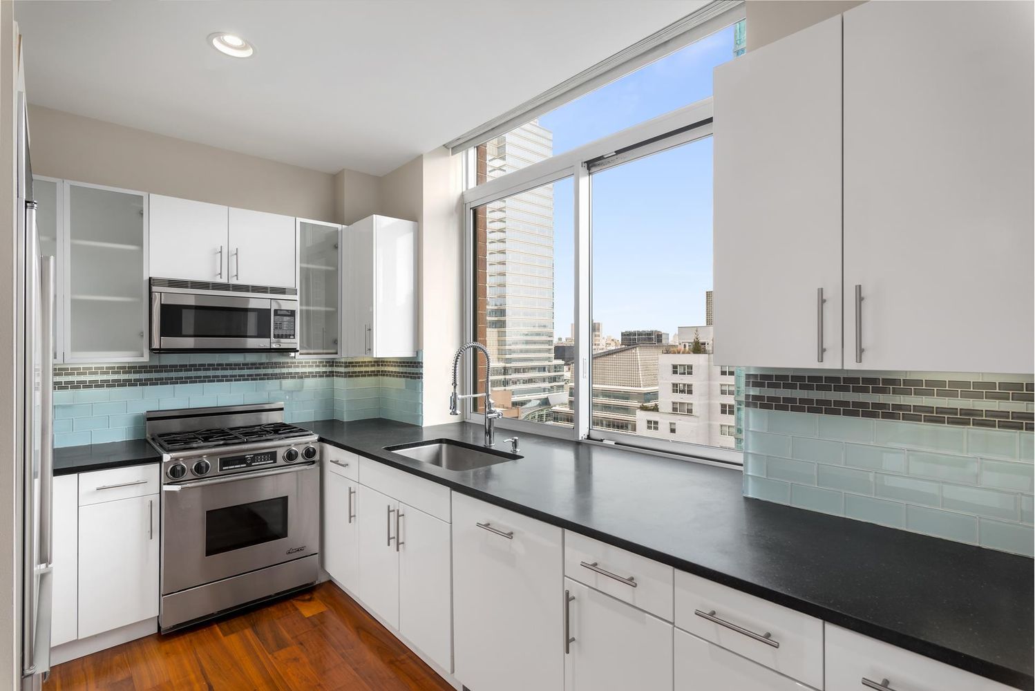 212 East 57th Street, Unit 18A Manhattan, NY 10022 - Photo 3 of 14 a kitchen with stainless steel appliances a stove sink and cabinets
