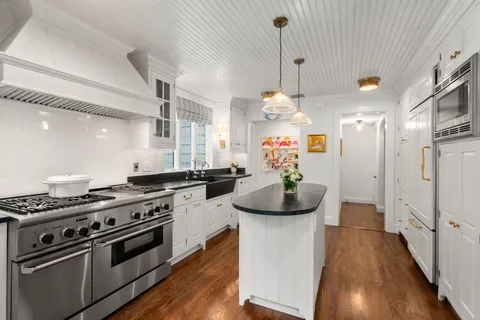 a kitchen with stainless steel appliances kitchen island granite countertop a stove and a wooden floors
