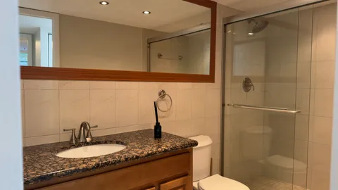 a bathroom with a granite countertop sink a mirror and shower