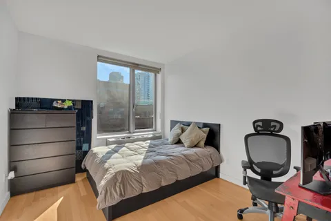 a bedroom with a bed a desk and chair with wooden floor