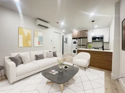a living room with furniture a kitchen view and a window