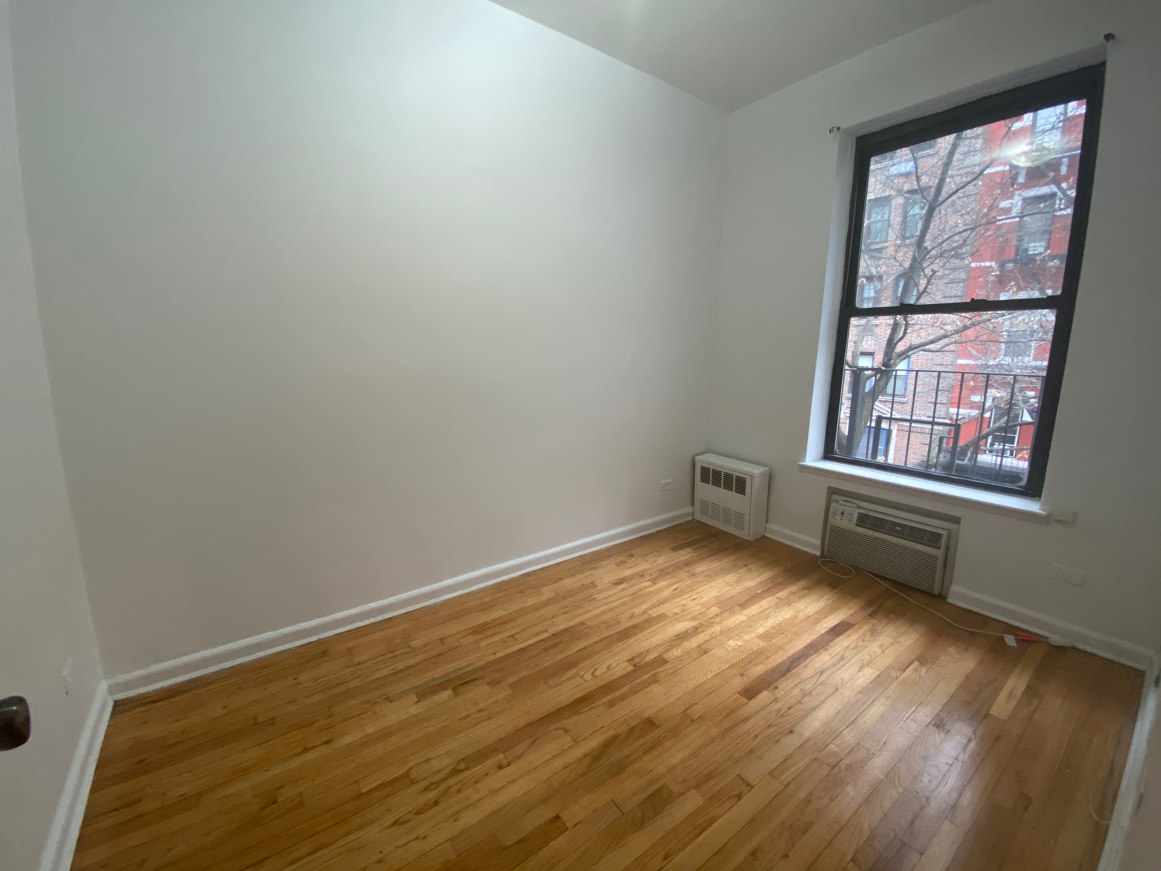 1240 Lexington Avenue, Unit 34 Manhattan, NY 10028 - Photo 9 of 11 an empty room with wooden floor and windows
