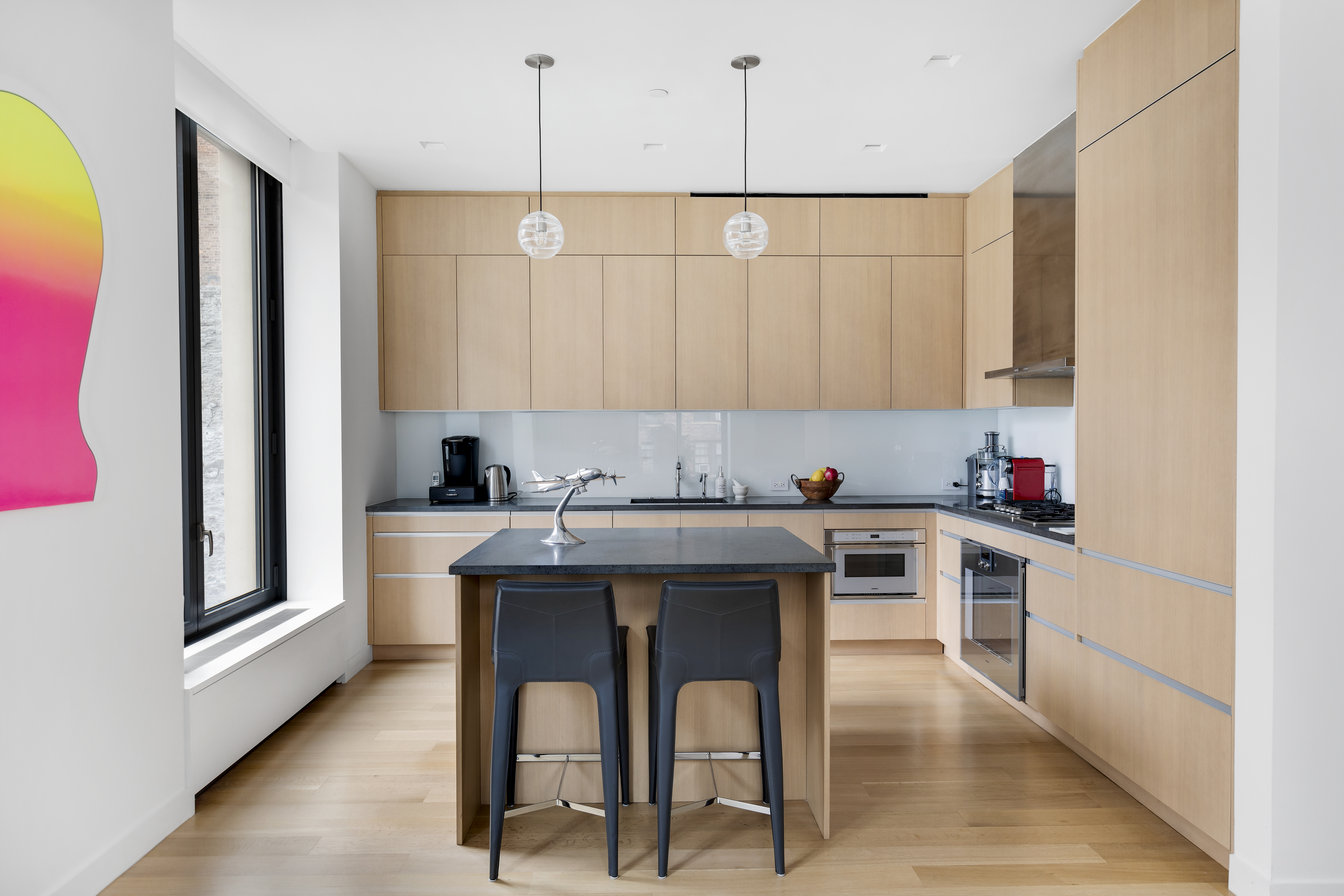 21 East 12th Street, Unit 5B Manhattan, NY 10003 - Photo 4 of 11 a kitchen with stainless steel appliances kitchen island granite countertop a sink and white cabinets