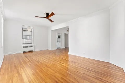 an empty room with wooden floor ceiling fan and windows