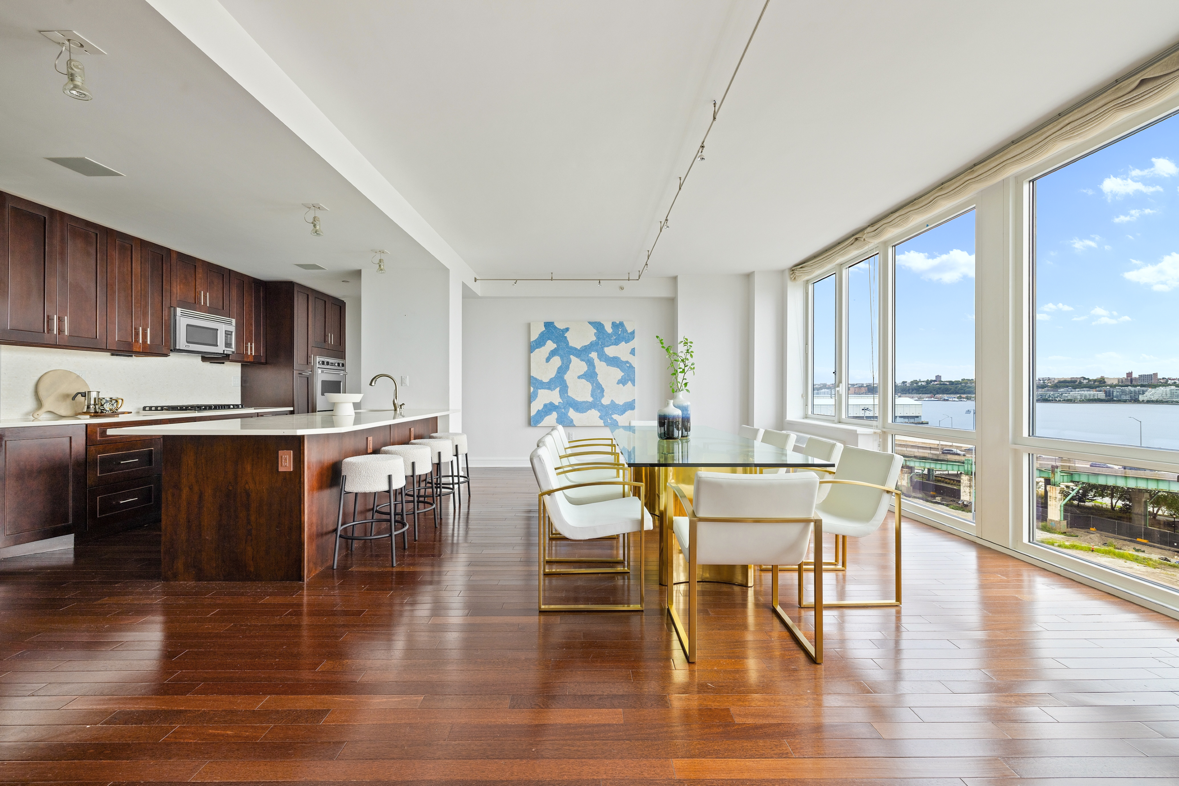 80 Riverside Boulevard, Unit 6B/L Manhattan, NY 10069 - Photo 2 of 17 a kitchen with stainless steel appliances wooden floor dining table and chairs