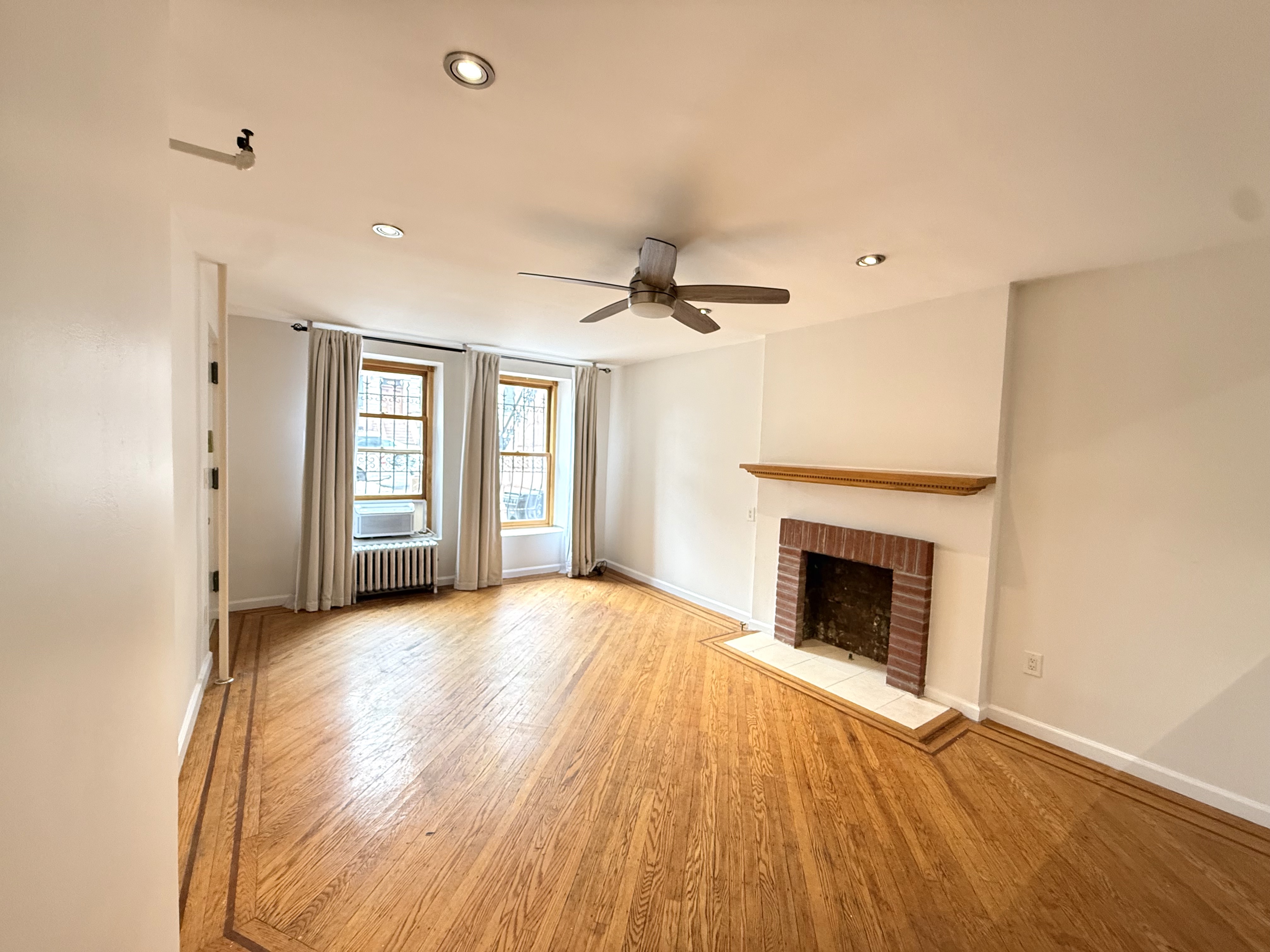 433 West 162nd Street, Unit 1 Manhattan, NY 10032 - Photo 1 of 13 a view of an empty room with a fireplace and a window