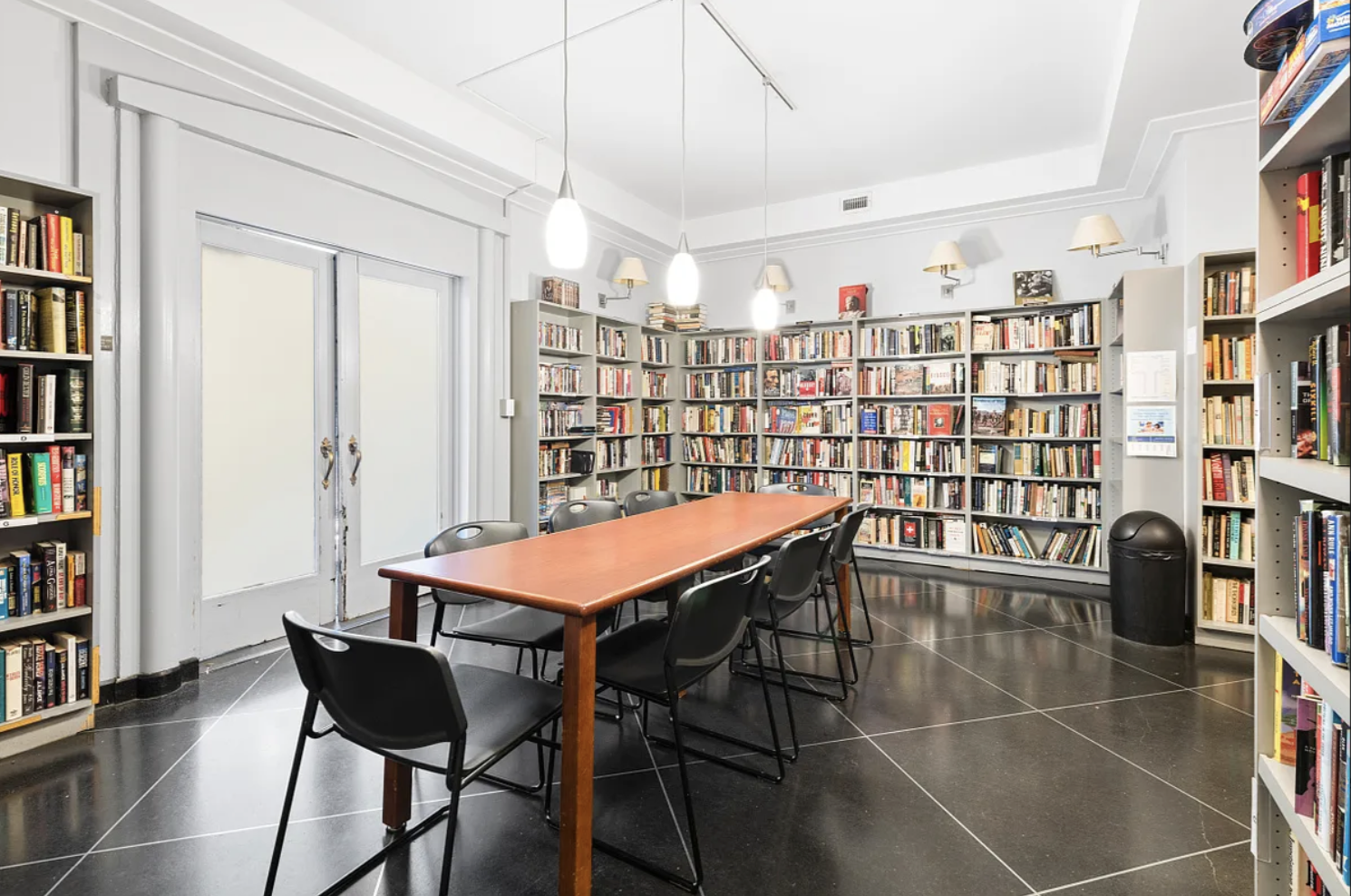2 5th Avenue, Unit 2R Manhattan, NY 10011 - Photo 11 of 12 a table and chairs in a room with a bookshelf