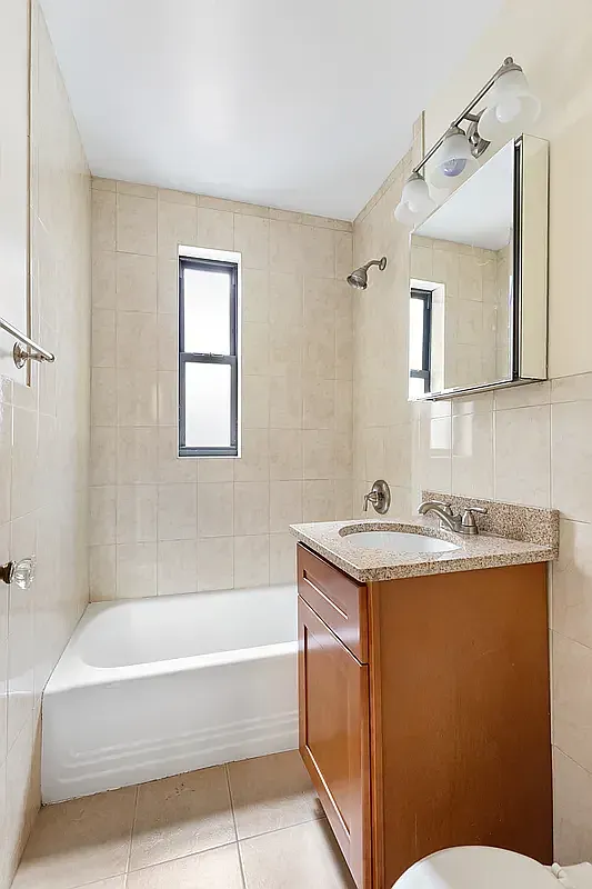 a bathroom with a granite countertop sink a mirror and a bathtub