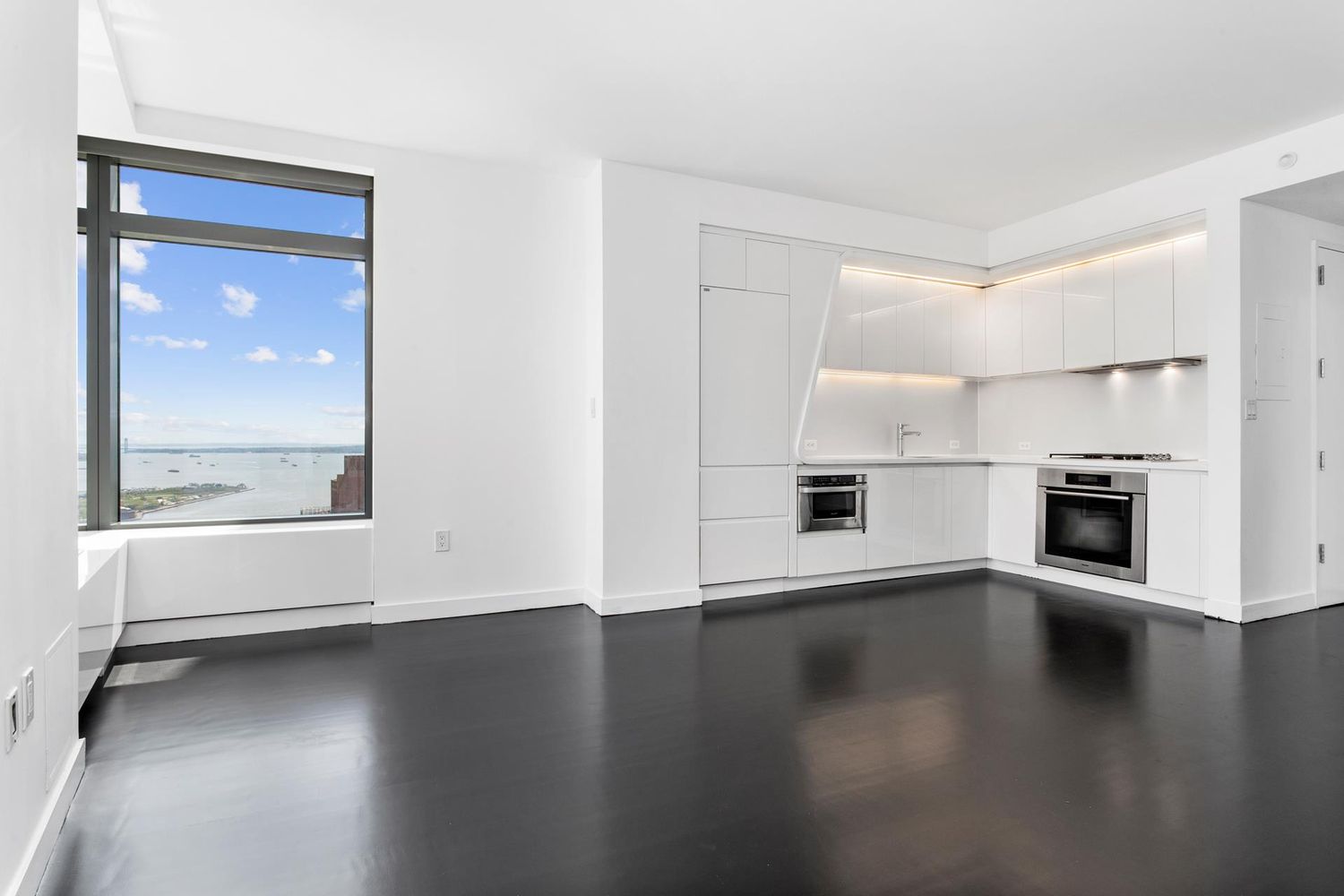 123 Washington Street, Unit PH54F Manhattan, NY 10006 - Photo 10 of 13 an empty room with wooden floor cabinet and windows