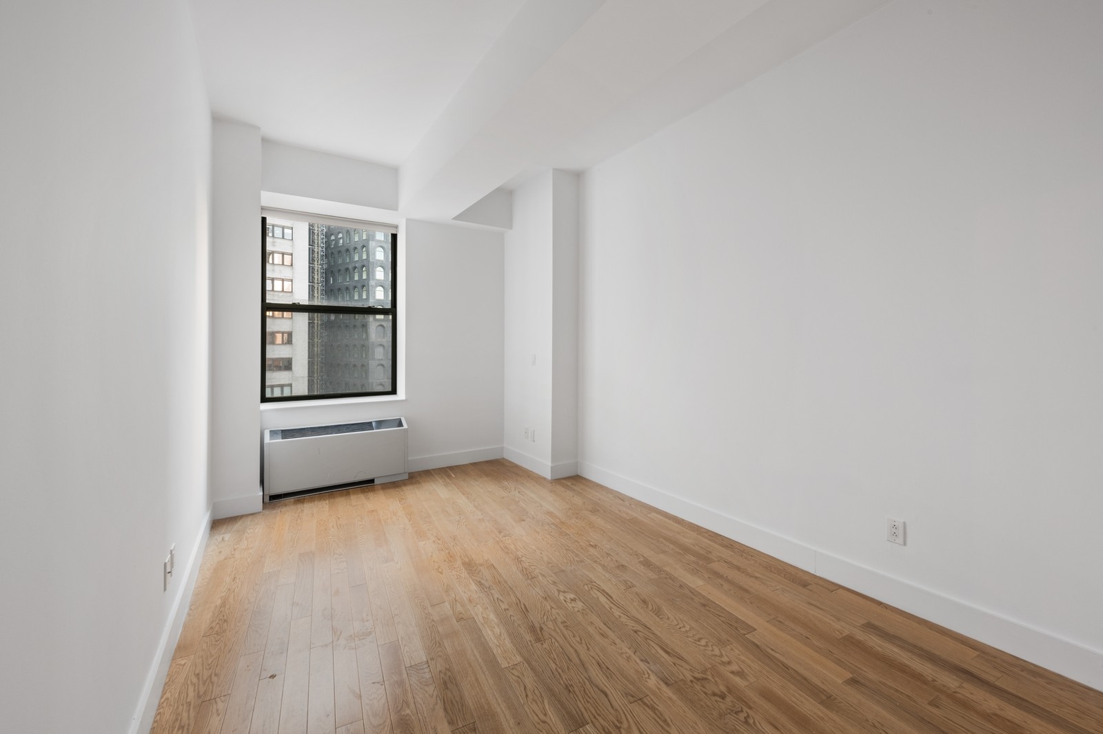 99 John Street, Unit 1711 Manhattan, NY 10038 - Photo 2 of 14 a view of an empty room with a window and wooden floor