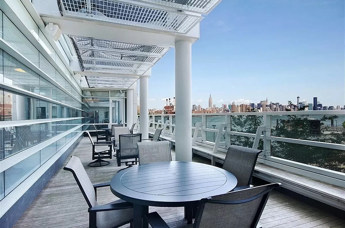 1 Northside Piers, Unit 18C Brooklyn, NY 11249 - Photo 9 of 12 a view of a roof deck with table and chairs with wooden floor and fence
