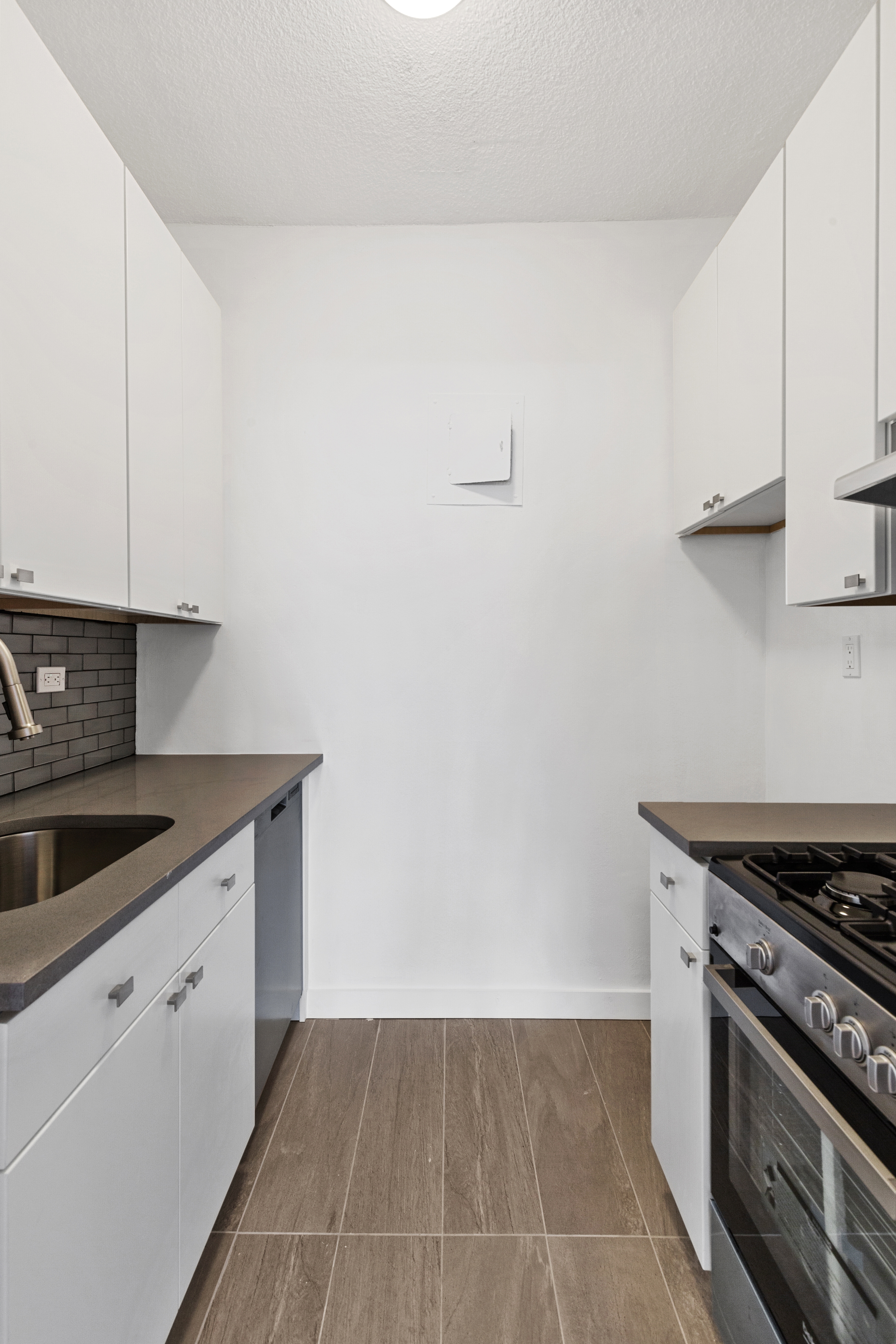 60 East 8th Street, Unit 9J Manhattan, NY 10003 - Photo 7 of 13 a kitchen with granite countertop a stove and a sink
