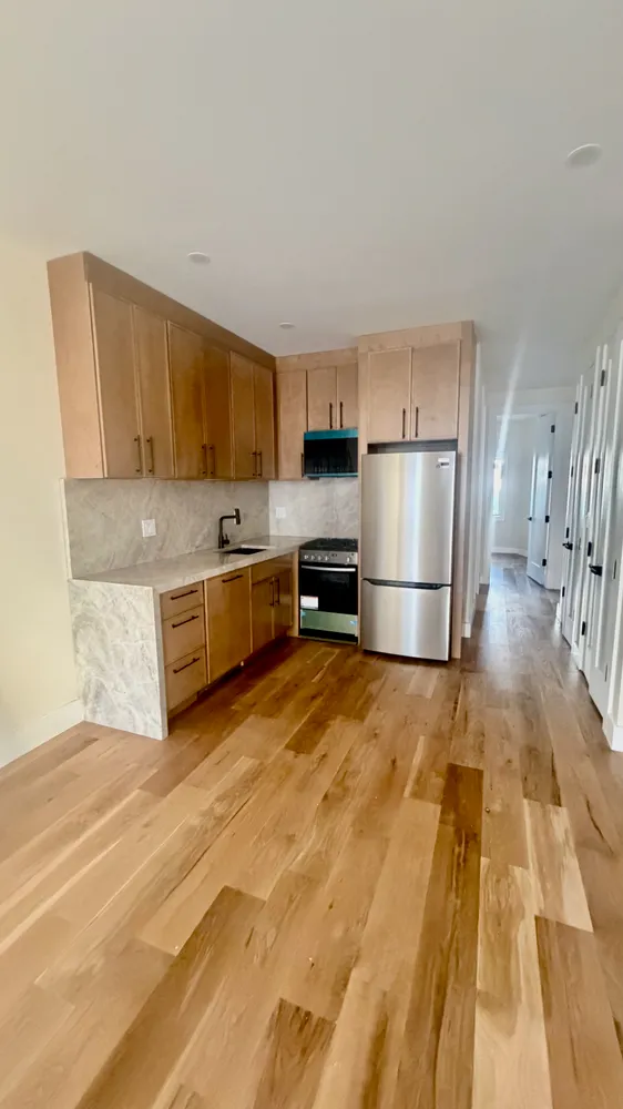 a kitchen with granite countertop a refrigerator and a stove top oven