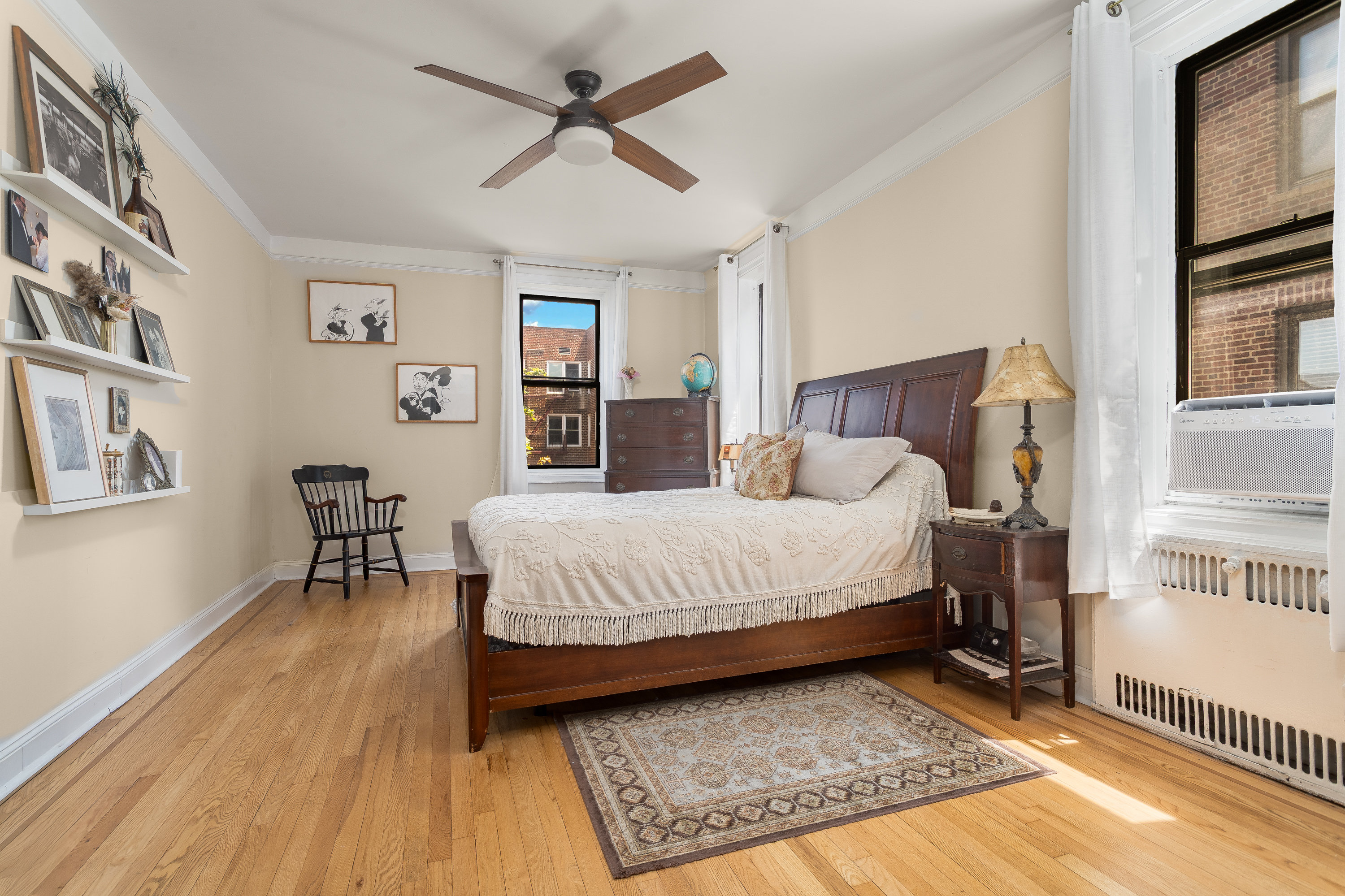 35-06 88th Street, Unit 5DD Queens, NY 11372 - Photo 11 of 18 a spacious bedroom with a bed a dresser and a book shelf