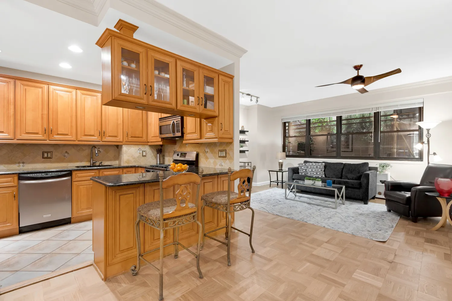 a kitchen with stainless steel appliances granite countertop a stove top oven a sink a dining table and chairs with wooden floor