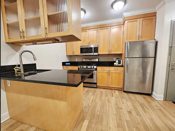 a kitchen with granite countertop a refrigerator a sink a stove top oven a dining table and chairs