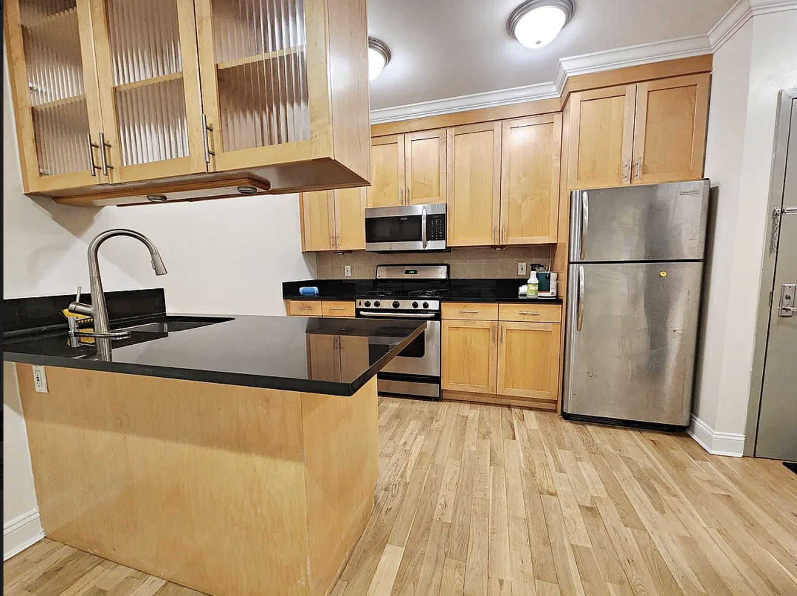 190 Meserole Avenue, Unit 2N Brooklyn, NY 11222 - Photo 1 of 10 a kitchen with granite countertop a refrigerator a sink a stove top oven a dining table and chairs