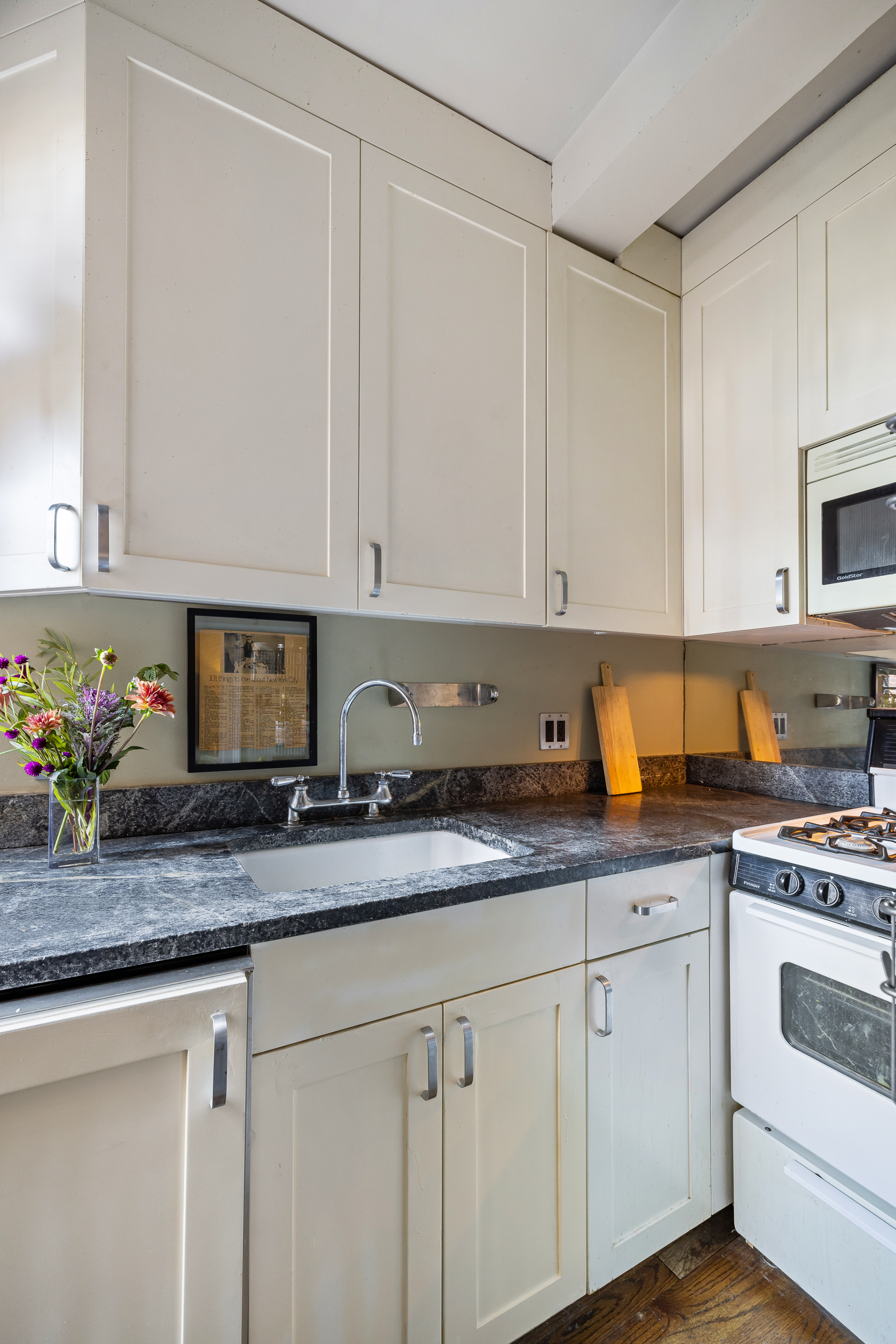 333 East 43rd Street, Unit 922 Manhattan, NY 10017 - Photo 6 of 14 a kitchen with granite countertop white cabinets and white appliances
