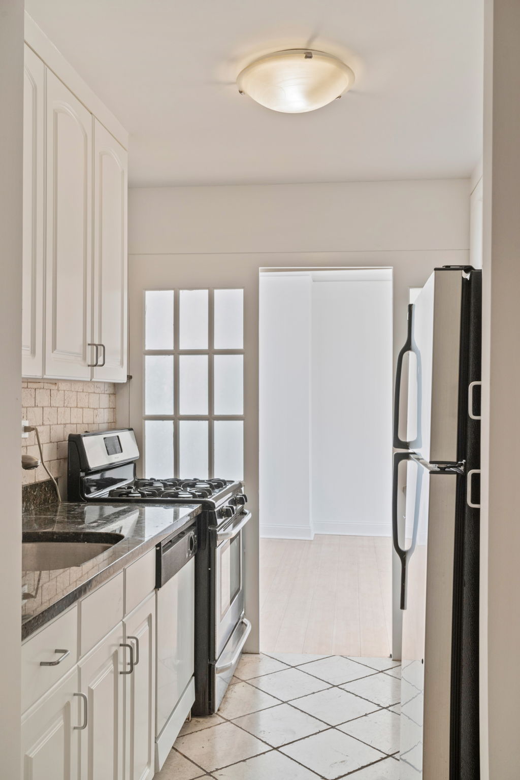 1623 3rd Avenue, Unit 31G Manhattan, NY 10128 - Photo 4 of 9 a kitchen with stainless steel appliances a refrigerator sink and cabinets