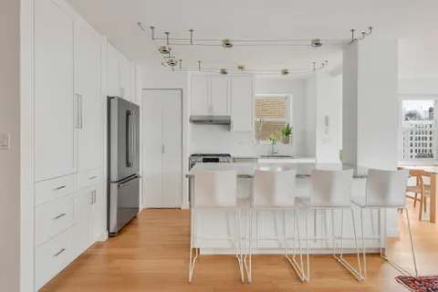a large white kitchen with a refrigerator a stove a sink and white cabinets