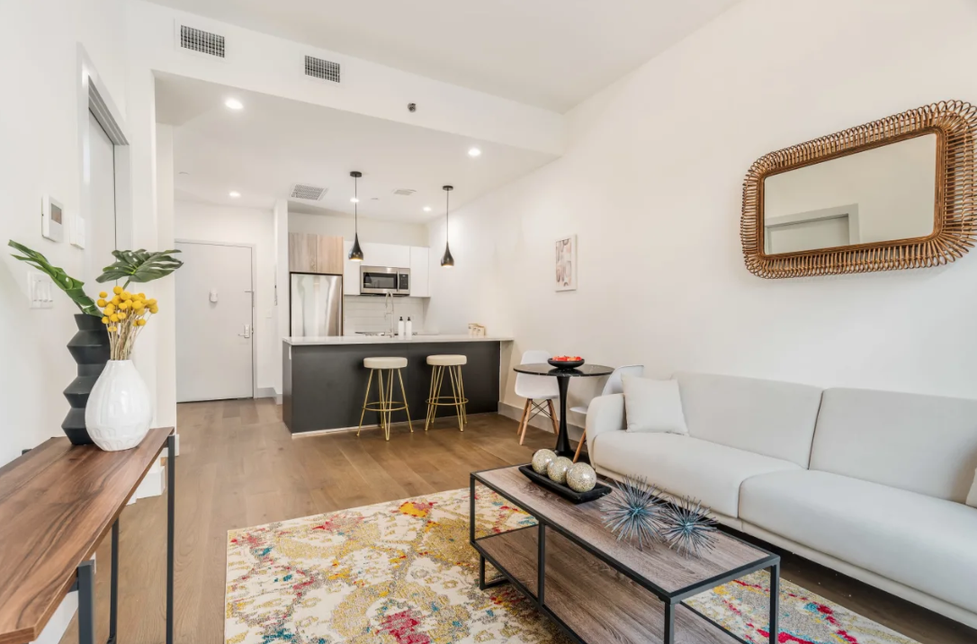 a living room with furniture a rug kitchen view and a table