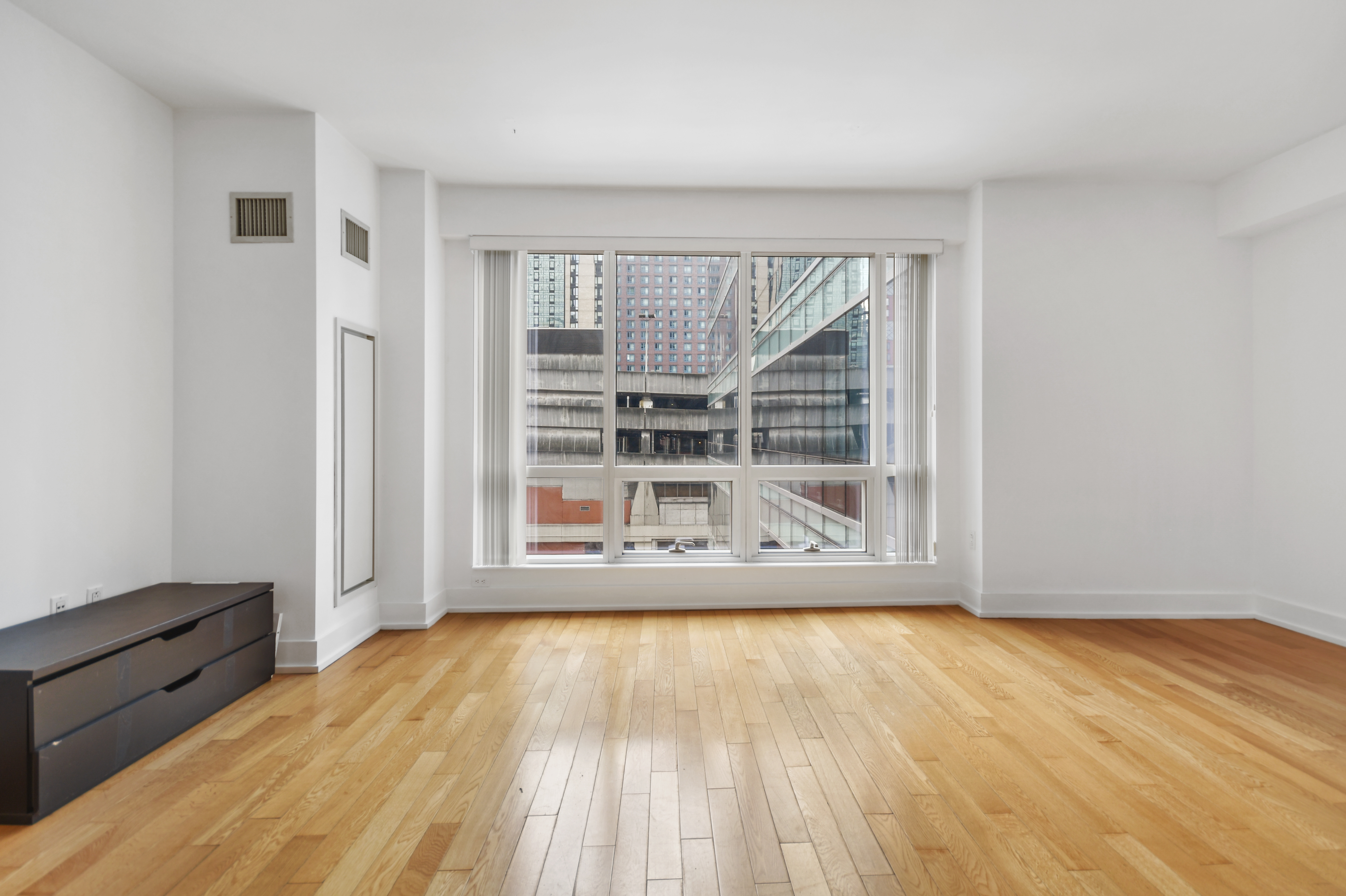 350 West 42nd Street, Unit 8H Manhattan, NY 10036 - Photo 2 of 11 an empty room with wooden floor and windows