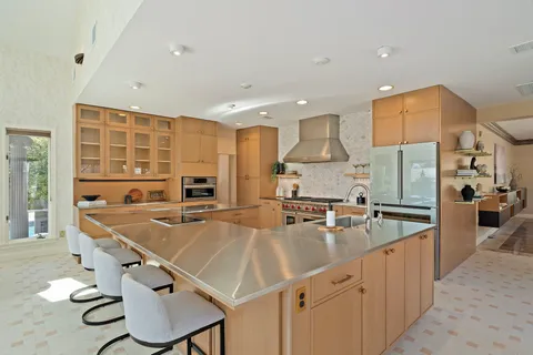 a large kitchen with kitchen island a large counter top space a sink a stove and a refrigerator