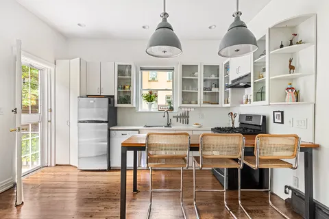 a dining room with stainless steel appliances a table chairs and a chandelier
