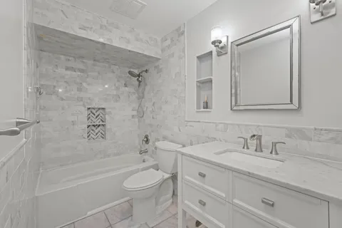 a bathroom with a sink a toilet a mirror a bathtub and shower