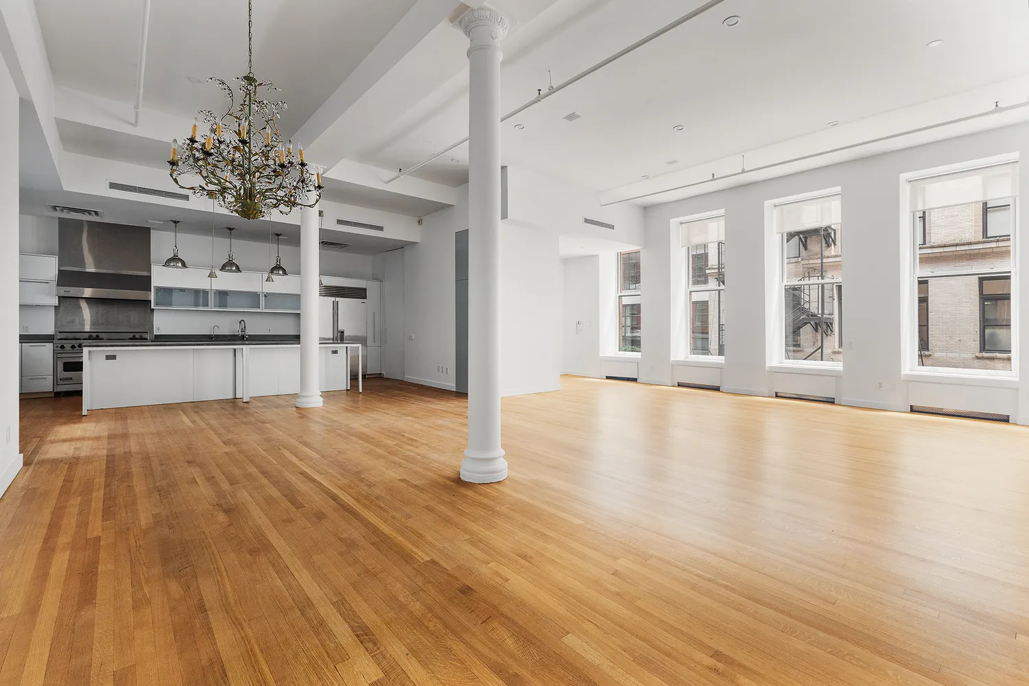 a view of an empty room with a kitchen and a window