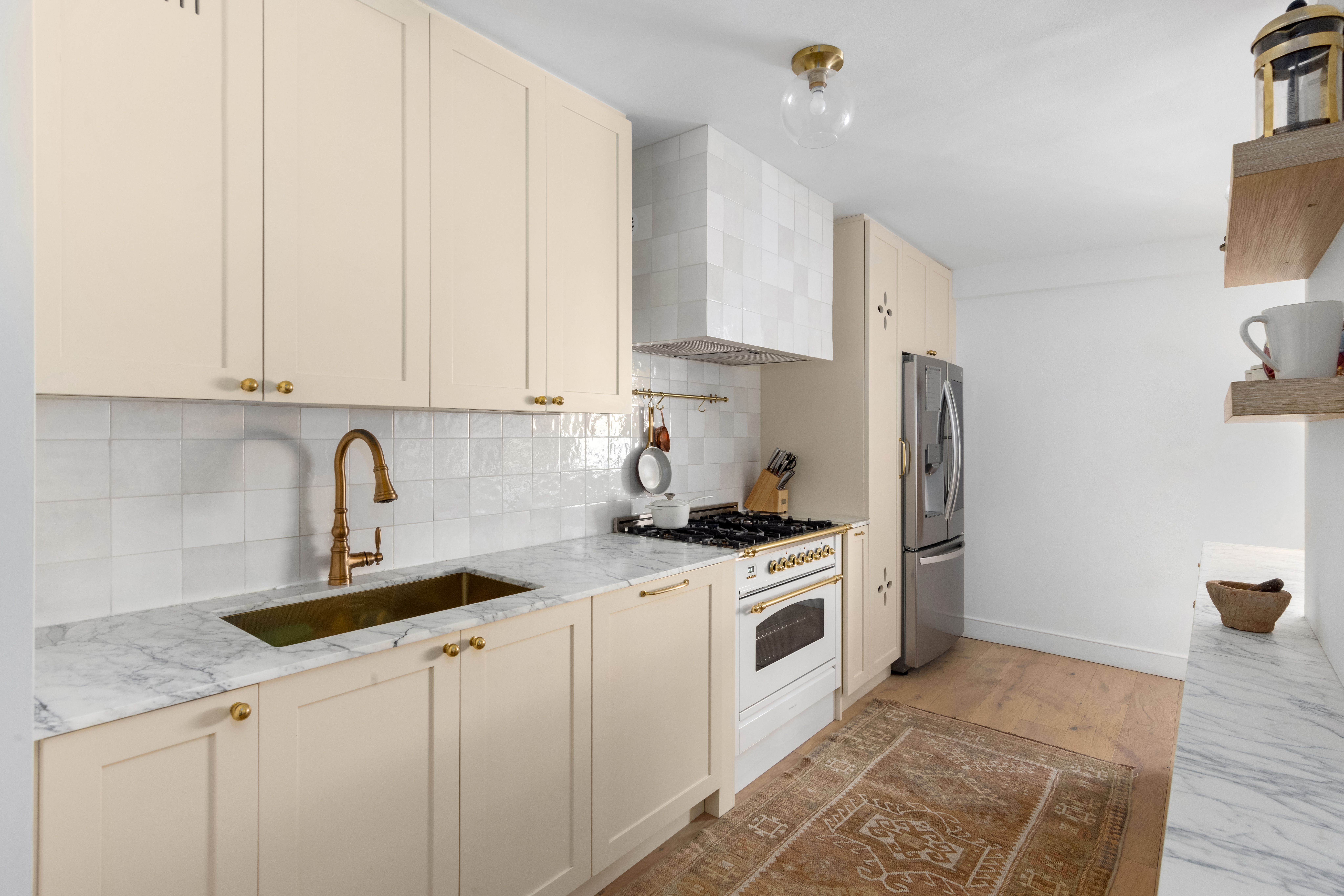 135 East 83rd Street, Unit 8/9C Manhattan, NY 10028 - Photo 4 of 15 a kitchen with stainless steel appliances granite countertop a sink a stove a refrigerator and cabinets