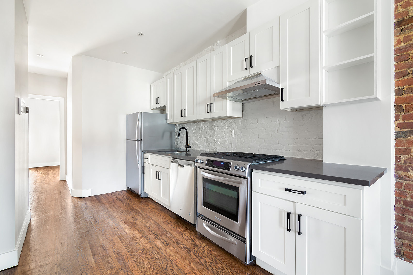 356 Halsey Street, Unit 2 Brooklyn, NY 11216 - Photo 4 of 9 a kitchen with granite countertop wooden floors and white stainless steel appliances