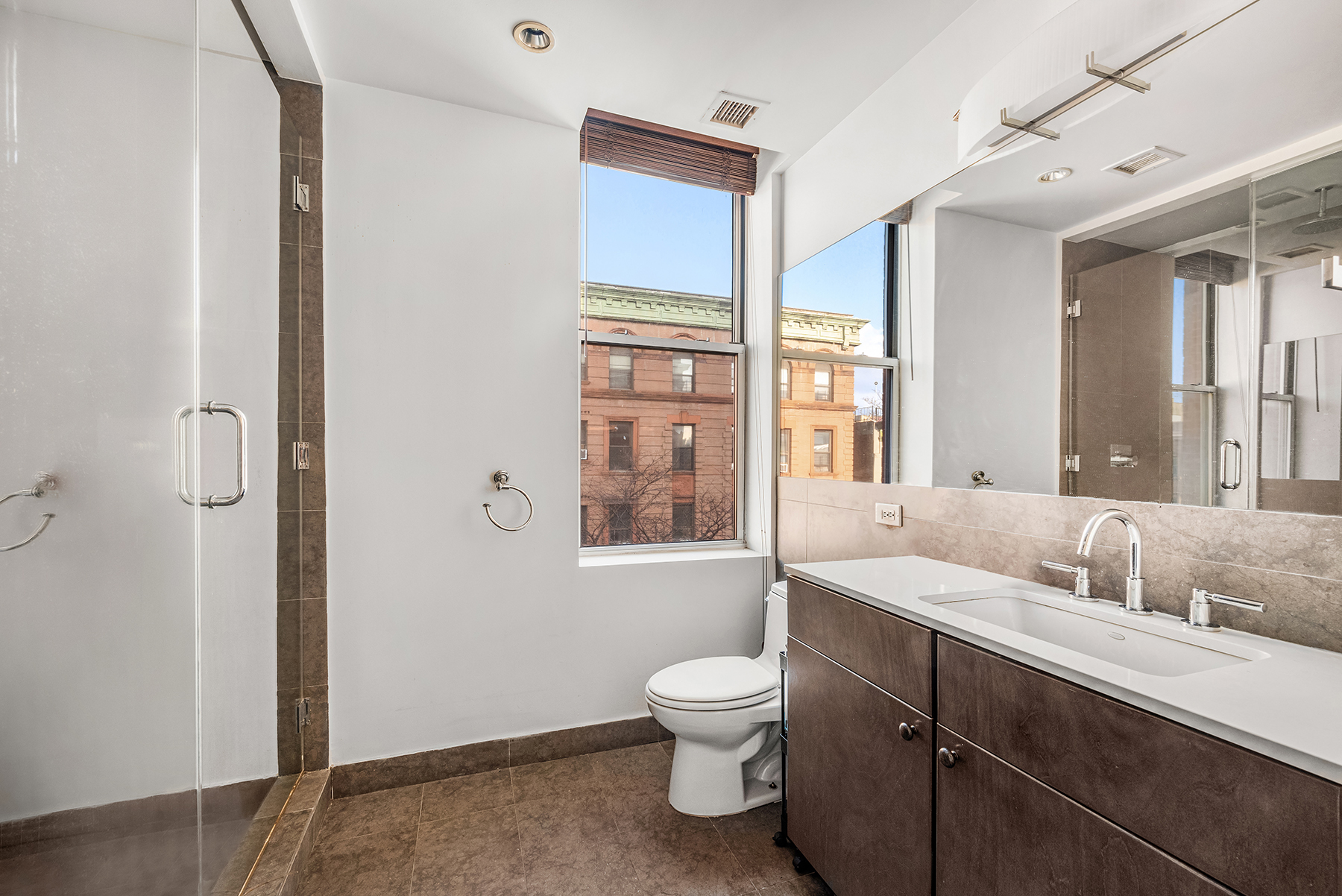 2605 Frederick Douglass Boulevard, Unit 4B Manhattan, NY 10030 - Photo 6 of 8 a spacious bathroom with a granite countertop sink toilet a large mirror a bathtub and next to a window