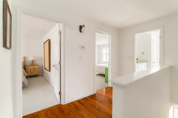 a view of a hallway with bathroom and wooden floor