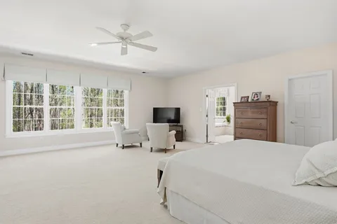 a spacious bedroom with a bed and a chair