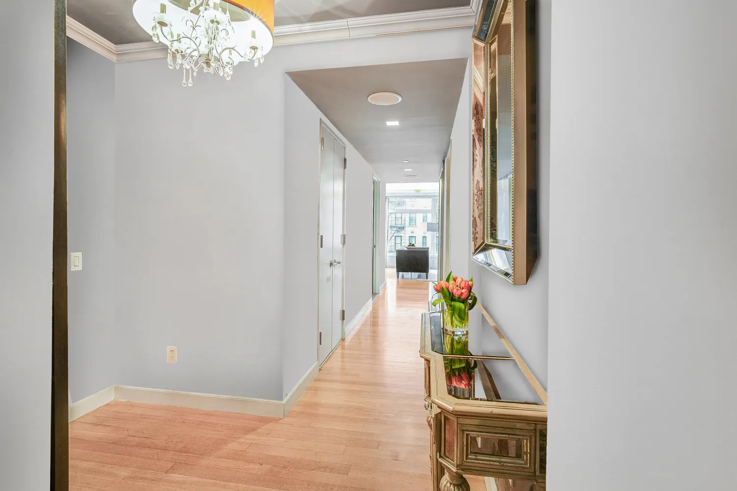 a hallway with wooden floor and a chandelier