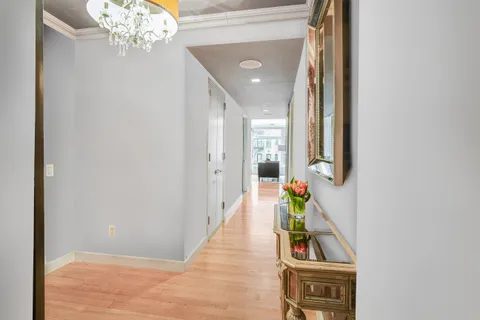 a hallway with wooden floor and a chandelier