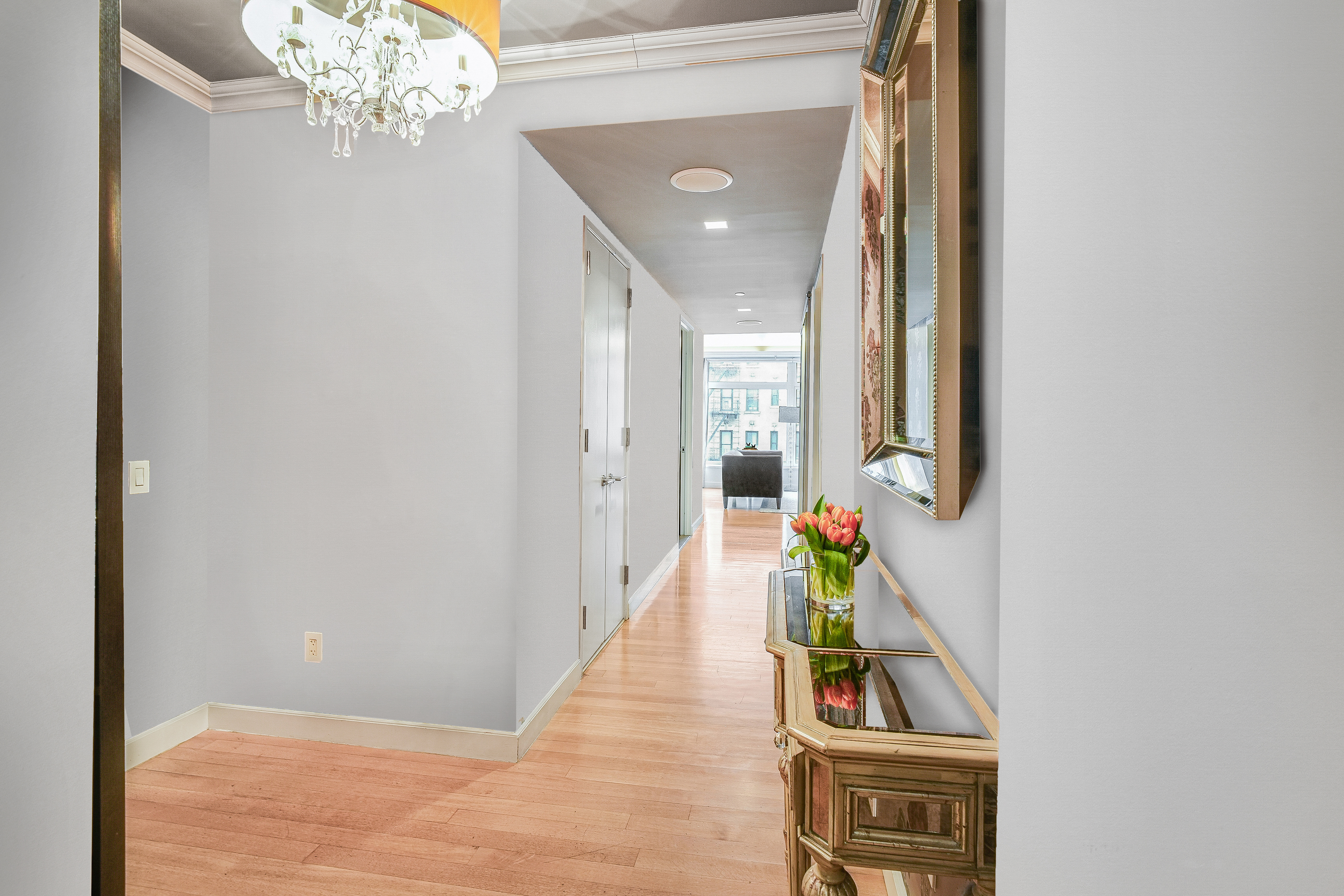 400 East 67th Street, Unit 3CD Manhattan, NY 10065 - Photo 4 of 28 a hallway with wooden floor and a chandelier