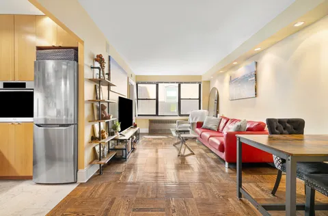 a living room with furniture a large window and a refrigerator