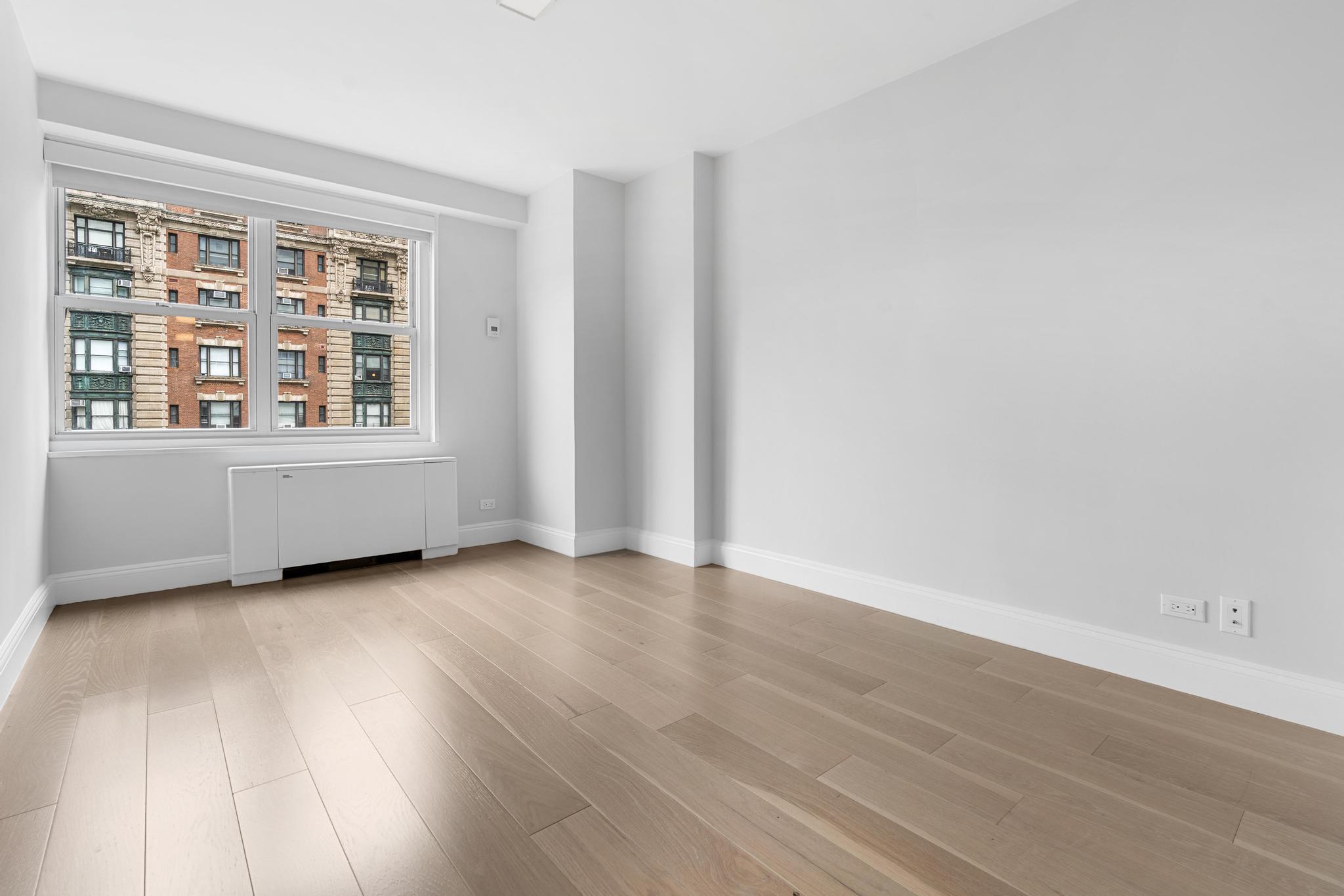 155 West 68th Street, Unit 1027 Manhattan, NY 10023 - Photo 3 of 8 an empty room with wooden floor and windows